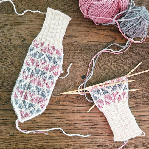 Moderne votter med geometrisk mønster. Hvit bunnfarge med grått og rosa mønster.