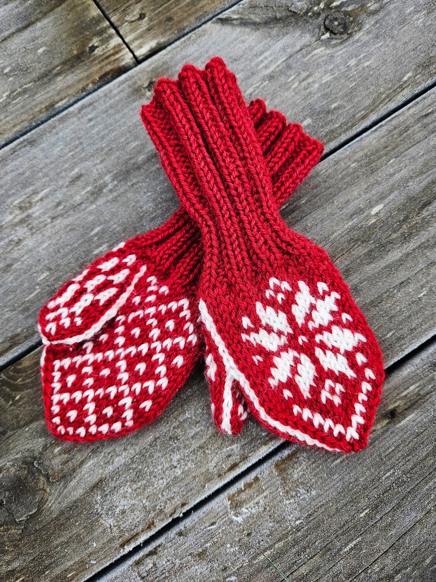 Strikkeoppskrift på selbuvotter til barn med tommel. Bildet viser røde selbuvotter, fine som julegavestrikk, på en rustikk trebakgrunn.